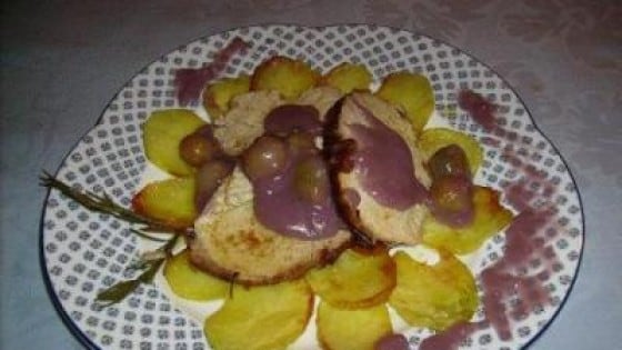 Arrosto di maiale su un letto di patate con salsa al vino e uva
