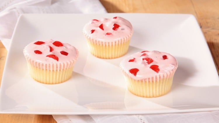 Cupcakes bianchi con copertura spumosa alle ciliegie e nocciole